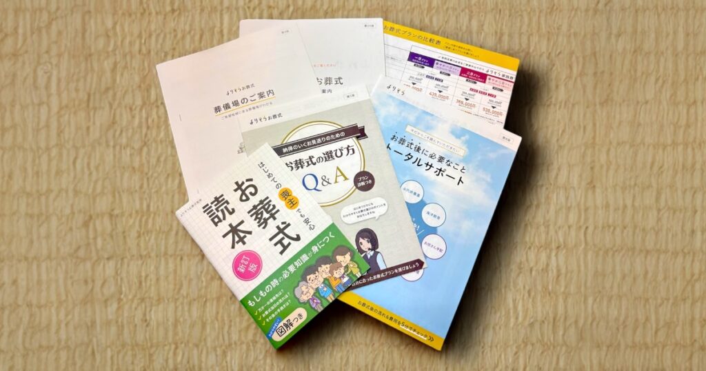 よりそうお葬式から届いた資料一式の写真。葬儀費用の比較表、葬儀の選び方、葬儀後のサポート冊子、ガイドブックなど、実際に手元に届いた内容がわかる。